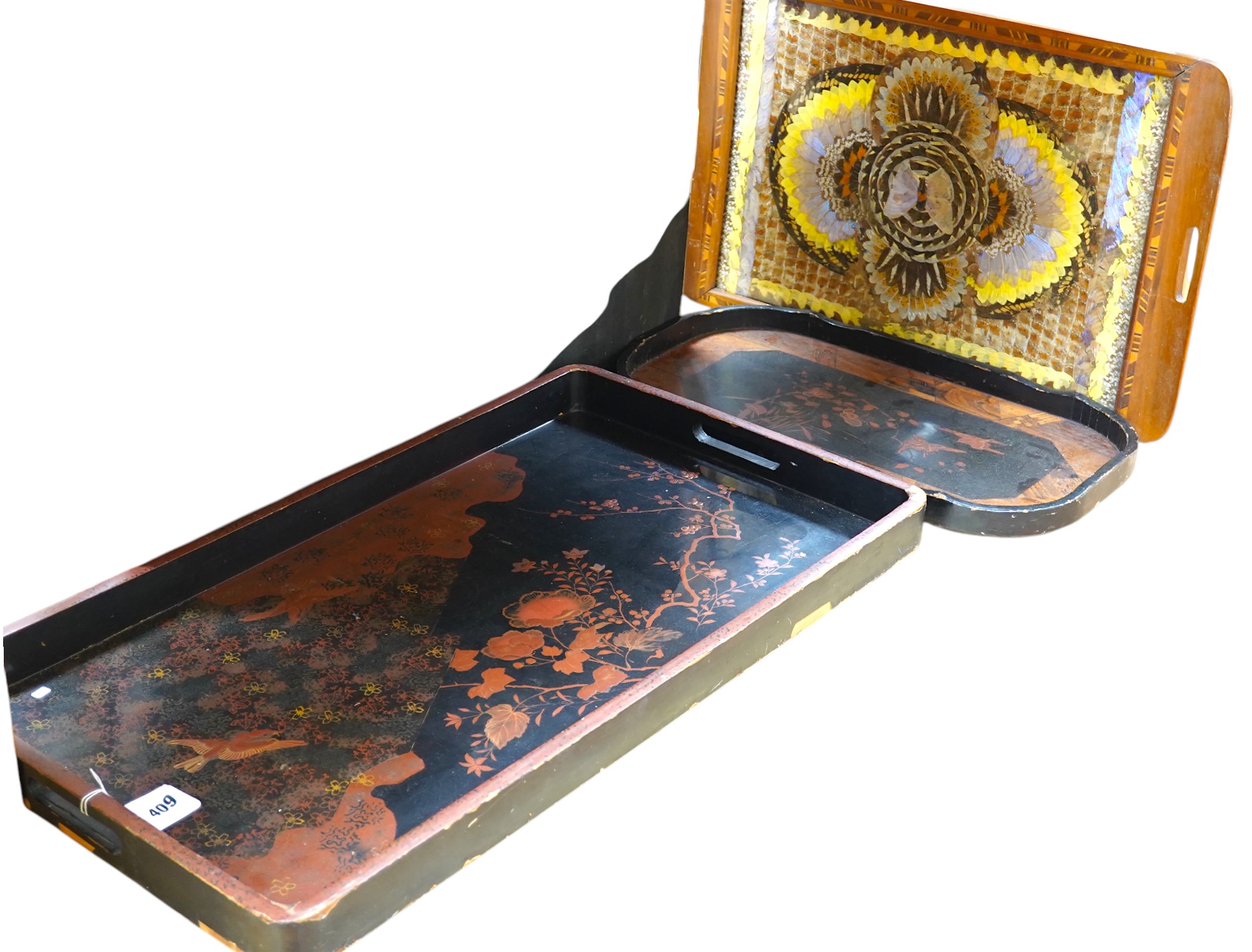 Three trays to include a butterfly wing example and a Japanese lacquered example decorated with birds and flowers, 75cm wide. Condition - poor to fair